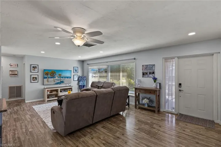 Living room with dark wood-type flooring, ceiling fan, and a textured ceiling