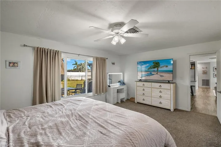 Carpeted bedroom with access to exterior, a textured ceiling, and ceiling fan