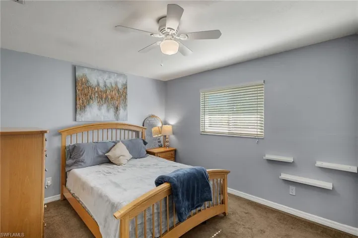 Bedroom with ceiling fan and dark colored carpet