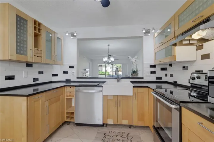 Kitchen with glass insert cabinets, stainless steel appliances, light tile patterned floors, and tasteful backsplash