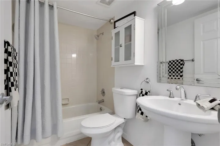Gust bathroom featuring toilet and shower / bath combination with curtain
