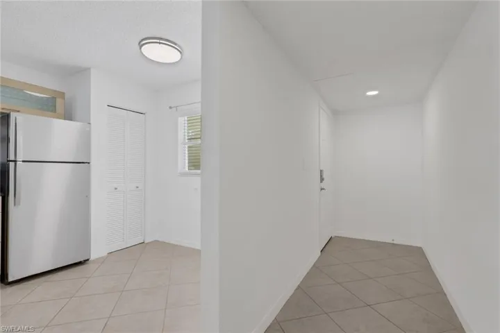 Hallway with light tile patterned flooring and baseboards