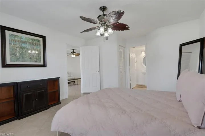 Primary Bedroom featuring light tile patterned floors, a closet, a ceiling fan, and connected bathroom