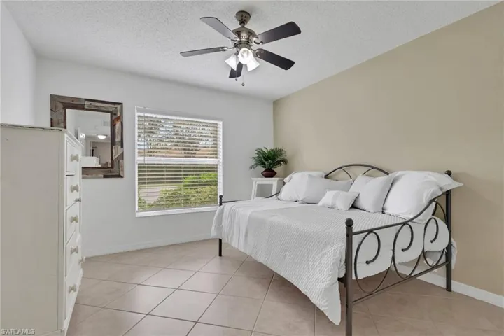 Guest Bedroom featuring a textured ceiling, a ceiling fan, and light tile patterned floors