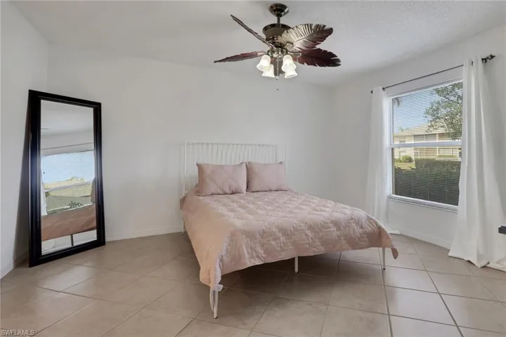 Primary Bedroom featuring a ceiling fan, light tile patterned floors, and a textured ceiling