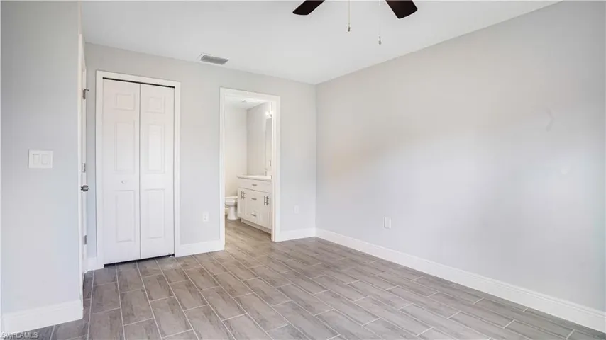 Unfurnished bedroom featuring light wood-type flooring, a closet, ceiling fan, and connected bathroom