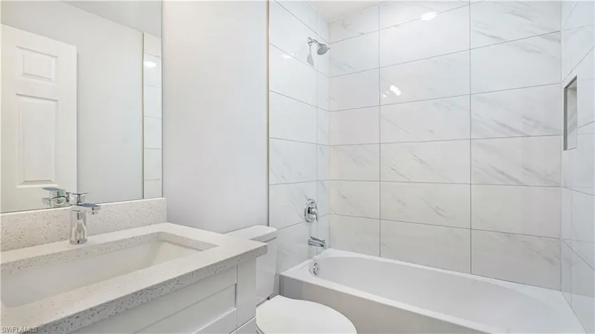 Full bathroom with tiled shower/bath combo, toilet, and vanity