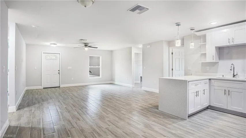 Kitchen featuring kitchen peninsula, white cabinetry, sink, and light wood-type flooring