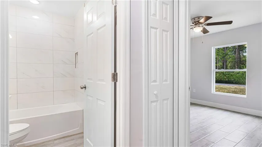 Bathroom featuring ceiling fan, toilet, and tiled shower/bath