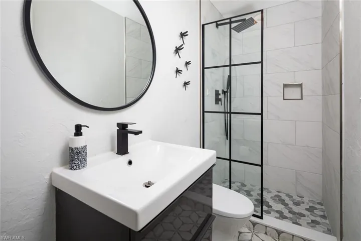 Bathroom featuring a tile shower, sink, and toilet