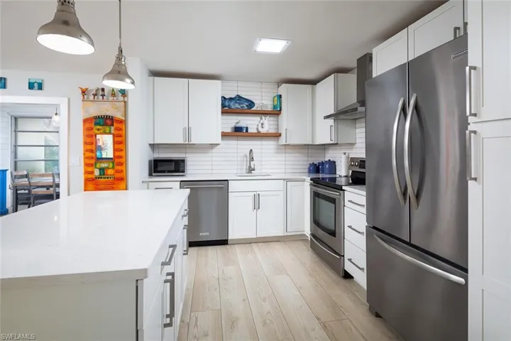 Kitchen featuring white cabinets, appliances with stainless steel finishes, sink, and wall chimney range hood