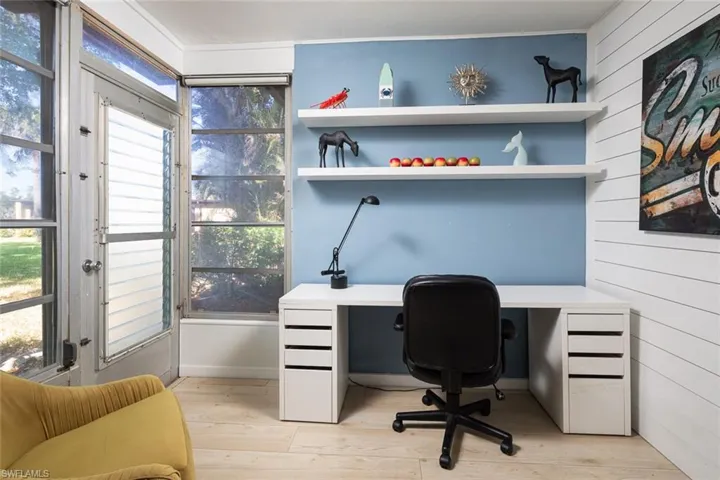 Home office with a wealth of natural light, light hardwood / wood-style flooring, and wooden walls