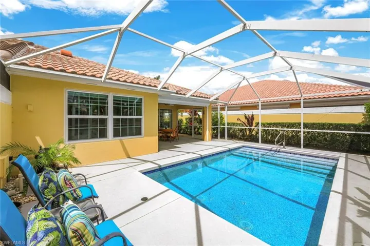Screened-in pool deck featuring a rectangular swimming pool with blue tile interior, a concrete patio, and a covered lanai