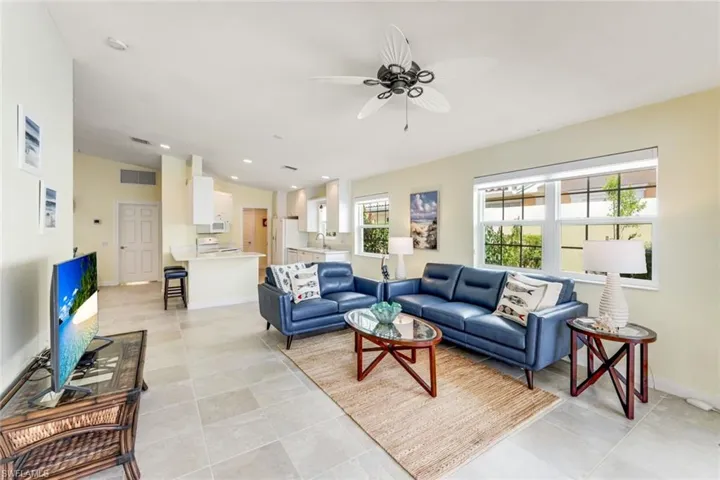 Spacious living area featuring high vaulted ceilings, large windows with white blinds, and light-toned tile flooring