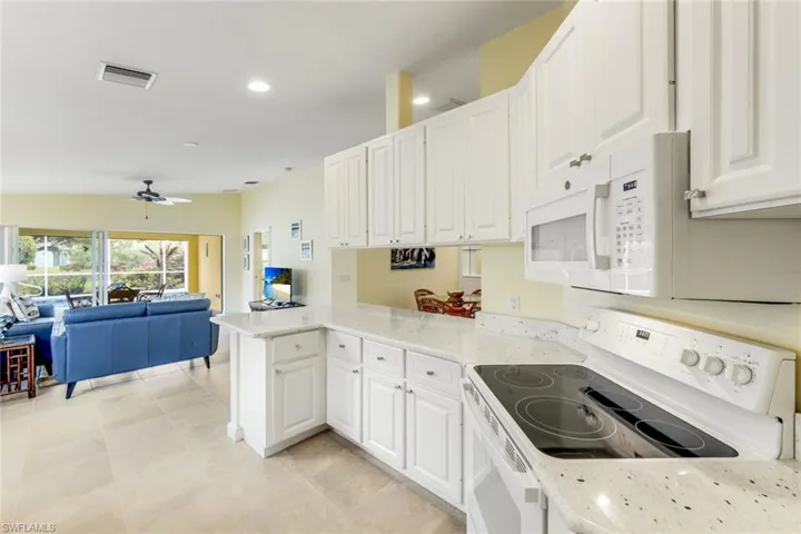Kitchen featuring white cabinetry, light-colored speckled countertops, and a built-in microwave