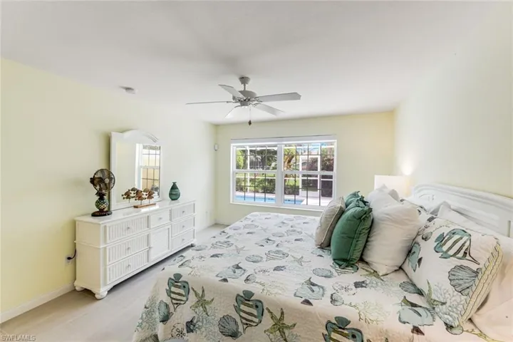 Spacious bedroom featuring light-toned walls, a ceiling fan, and light wood-finish flooring