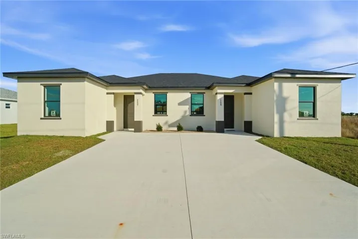 Prairie-style home featuring a front lawn, driveway, and stucco siding
