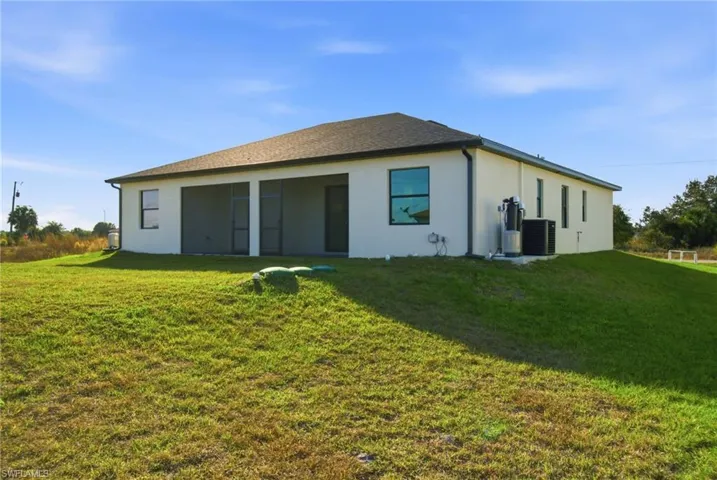 Back of property featuring stucco siding, a lawn, and roof with shingles