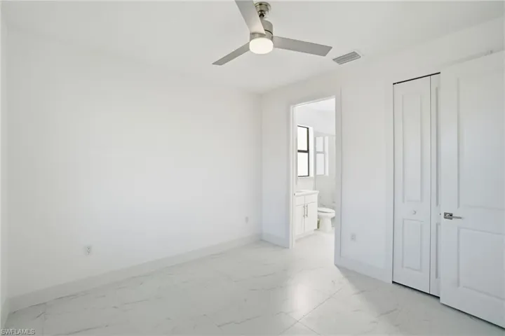 Unfurnished bedroom with light marble finish flooring, a ceiling fan, and ensuite bathroom
