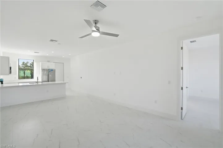 Unfurnished living room featuring light marble finish floors, ceiling fan, and recessed lighting