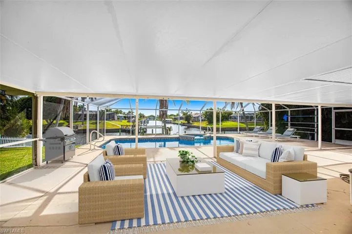 View of patio featuring glass enclosure, outdoor lounge area, a water view, a pool with connected hot tub, and a sunroom