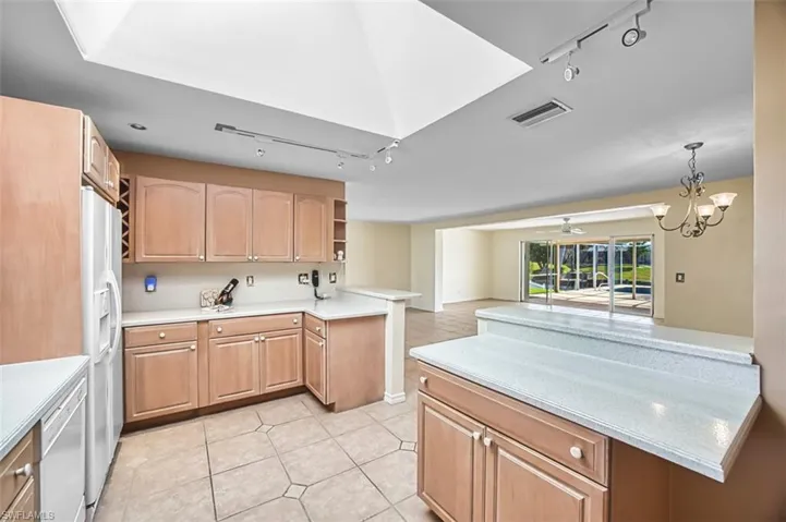 Kitchen featuring rail lighting, a peninsula, white appliances, and open shelves