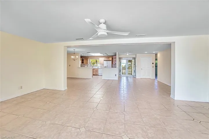Unfurnished living room featuring a ceiling fan, a chandelier, and light tile patterned floors