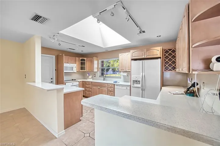 Kitchen featuring a peninsula, track lighting, open shelves, and glass insert cabinets