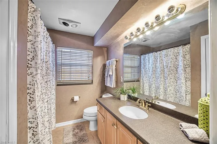 Guest bathroom featuring vanity, curtained shower, light tile patterned floors, and a textured wall
