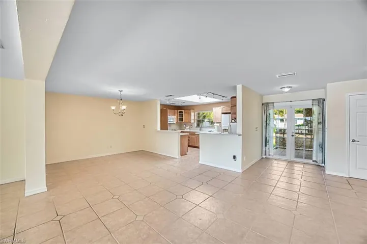 Unfurnished living room featuring french doors, a chandelier, and light tile patterned flooring