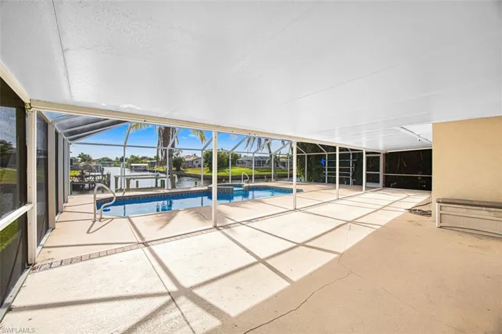 View of swimming pool featuring a sunroom, a patio, glass enclosure, and a water view