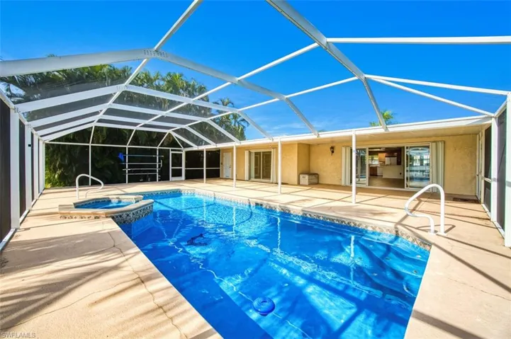 View of pool featuring a sunroom, glass enclosure, a pool with connected hot tub, and a patio