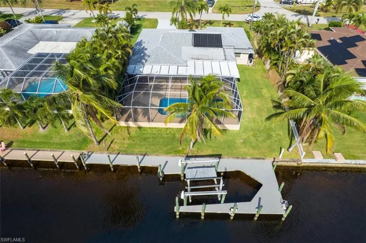 Aerial view of property and surrounding area featuring a large body of water and a pool area