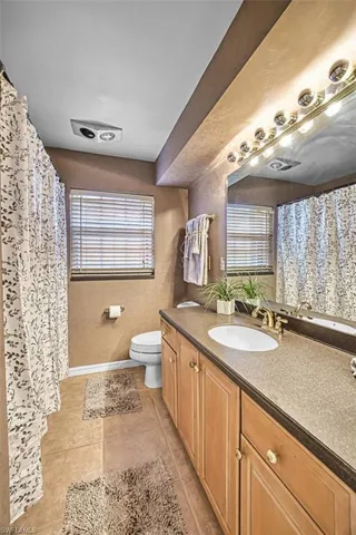 Full bathroom with curtained shower, vanity, and light tile patterned floors