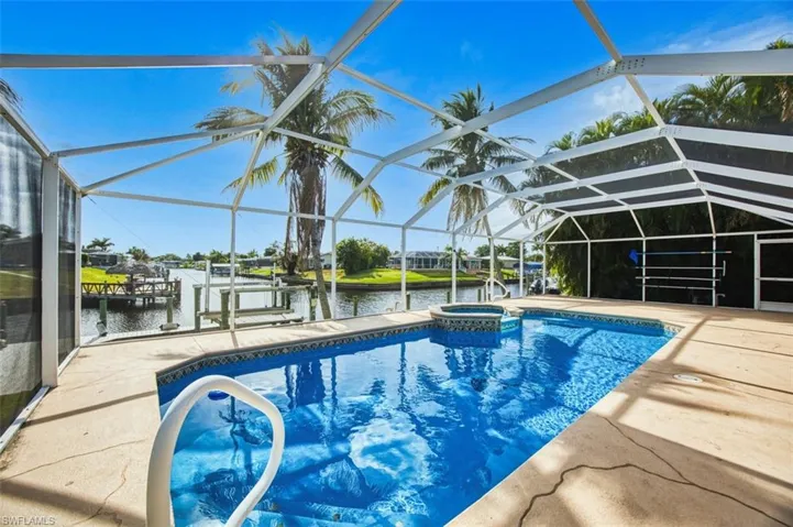 View of pool featuring a sunroom, a water view, a lanai, a pool with connected hot tub, and boat lift