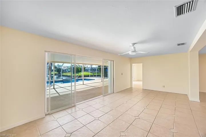 Empty room with ceiling fan, a sunroom, and light tile patterned floors