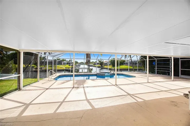 View of swimming pool with a pool with connected hot tub, a water view, a lanai, and a patio area