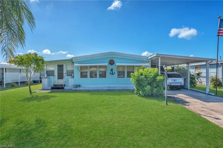 Rear view of house featuring a lawn, driveway, and a carport