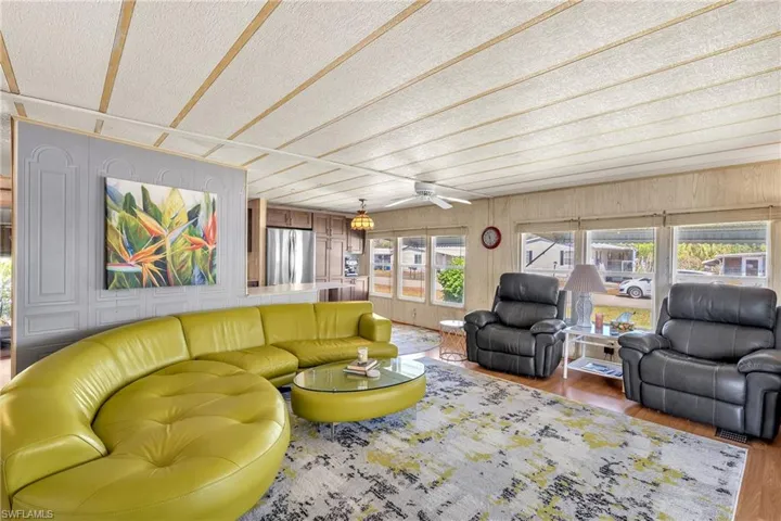 Living area featuring light wood-style flooring, wooden walls, and ceiling fan