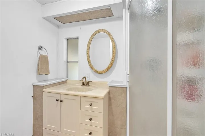Full bathroom featuring vanity, a shower stall, and tile walls
