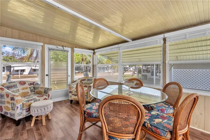 Sunroom featuring vaulted ceiling, wood finished floors, and wood walls