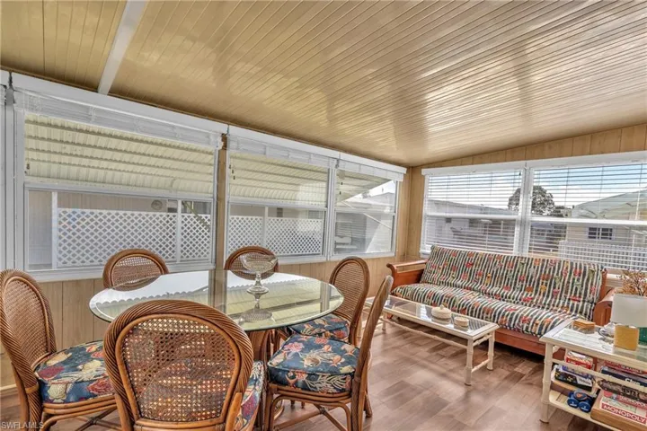 Sunroom / solarium featuring wood finished floors, wooden walls, and lofted ceiling
