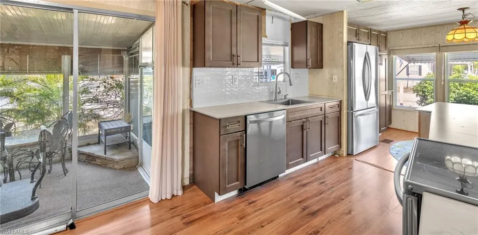 Kitchen featuring stainless steel appliances, light wood-style flooring, decorative light fixtures, and healthy amount of natural light