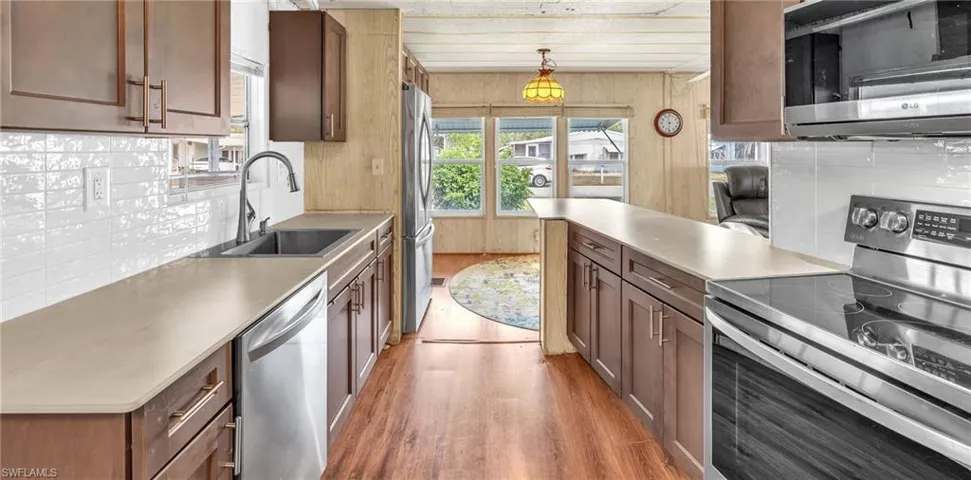Kitchen with stainless steel appliances, light wood-style flooring, a peninsula, and tasteful backsplash
