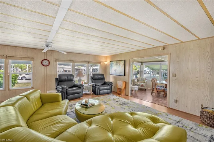 Living room featuring wood finished floors, wooden walls, and a ceiling fan