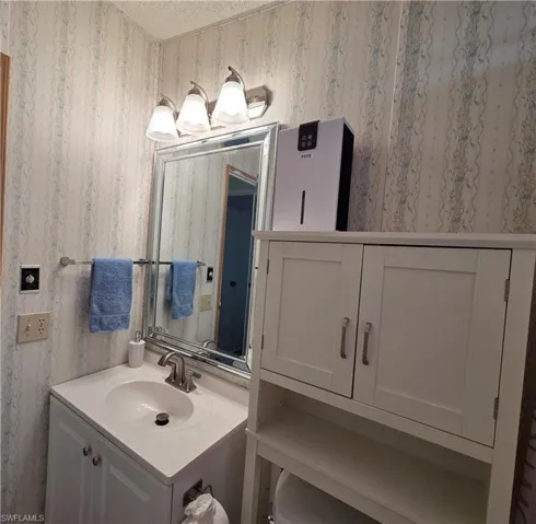 Bathroom vanity with integrated sink, brushed nickel faucet, and a large framed mirror