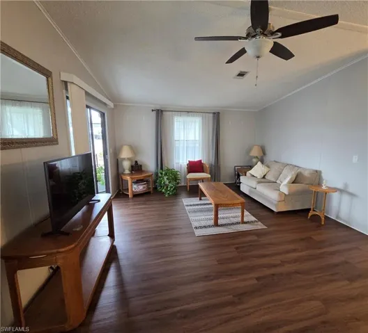 Expansive living area featuring rich wood-finish flooring and ceiling fan.