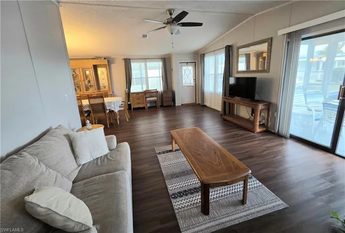 Spacious living room featuring wood-finish flooring, vaulted ceilings, and a ceiling fan