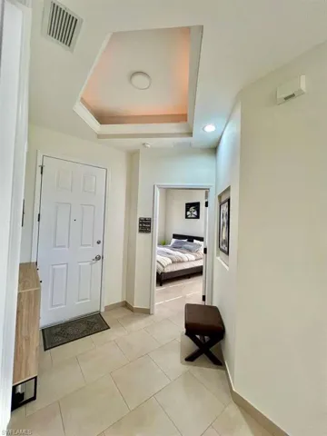 Entryway featuring light-toned large format tile flooring and a recessed ceiling detail with integrated lighting