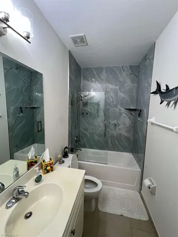 Bathroom featuring a full tub with a glass shower enclosure and a shower system with a handheld showerhead